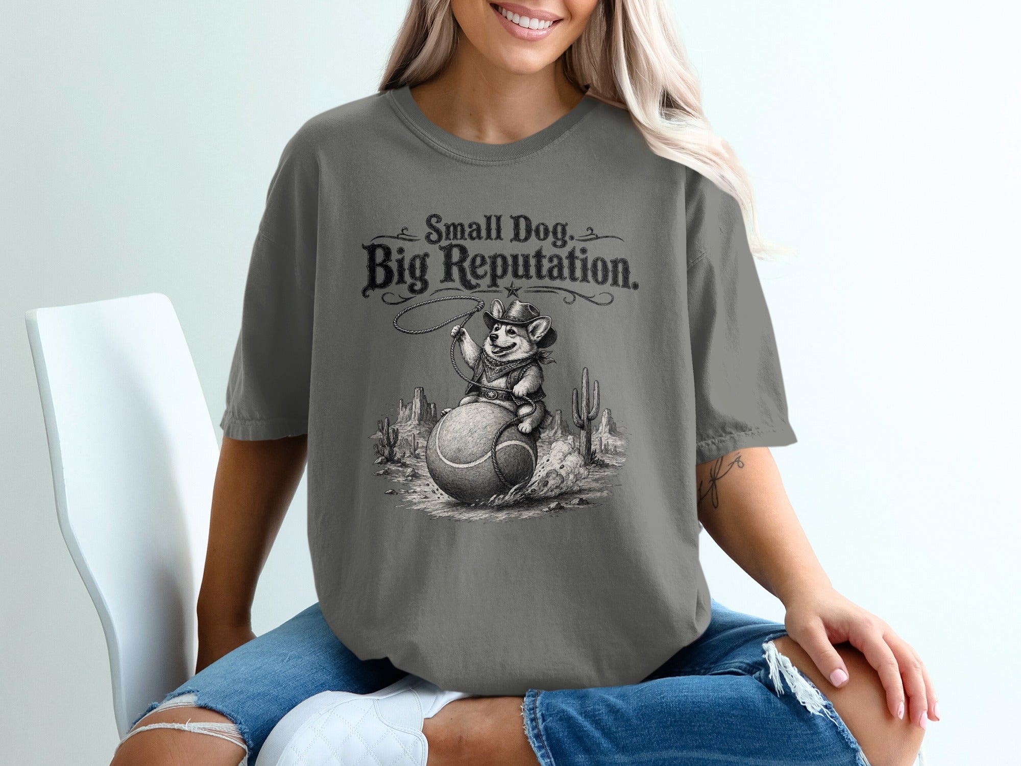 T-shirt graphic: "Small Dog, Big Reputation" with a dog riding a tennis ball in the desert.