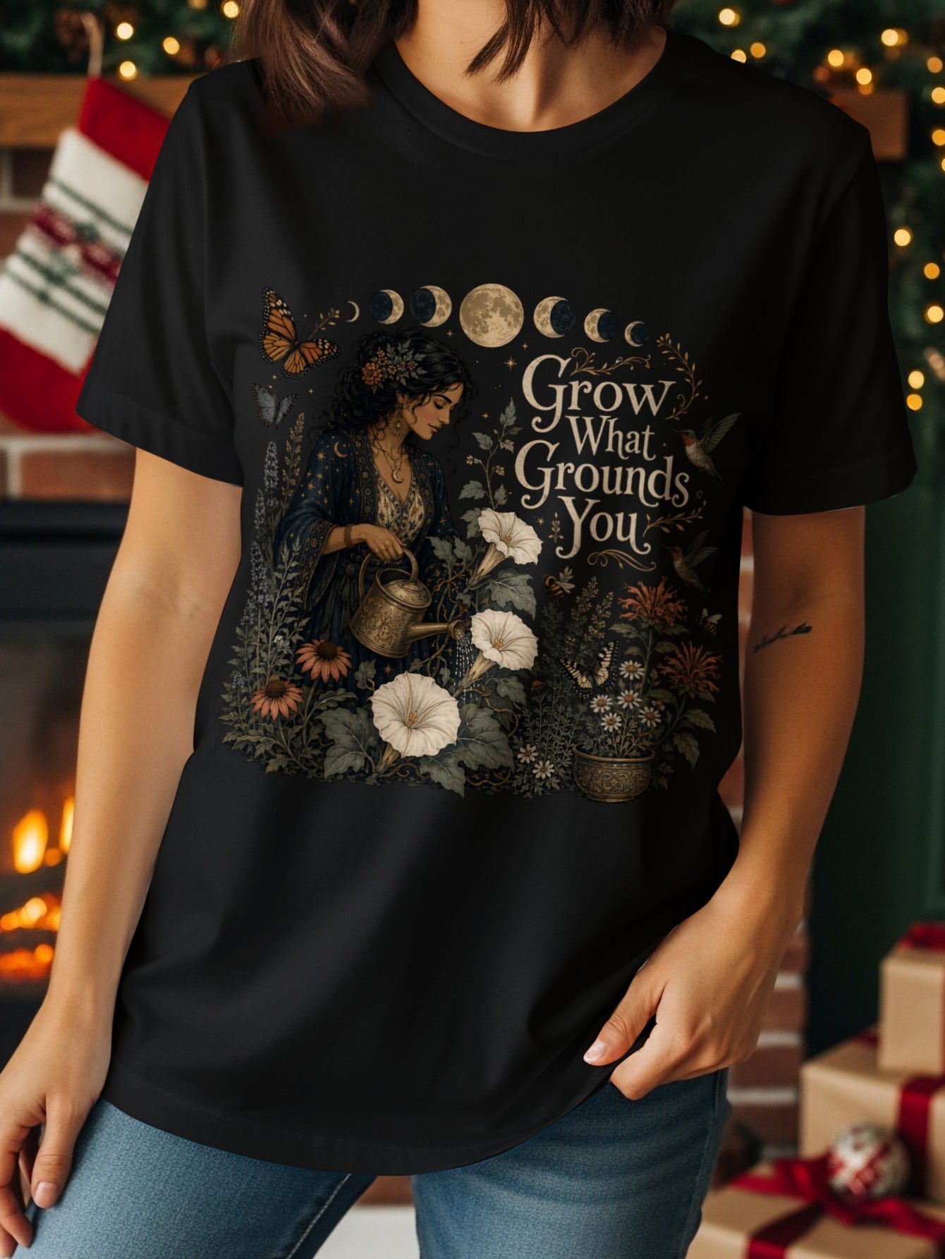 Black t-shirt with a woman watering flowers with text "Grow What Grounds You".
