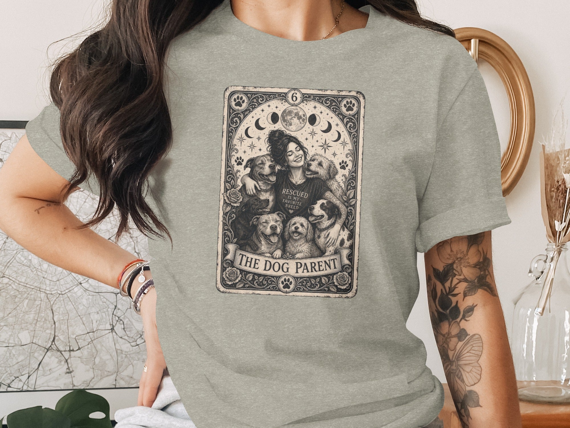 Light grey t-shirt with a tarot card design of a woman embracing dogs, reading "The Dog Parent".
