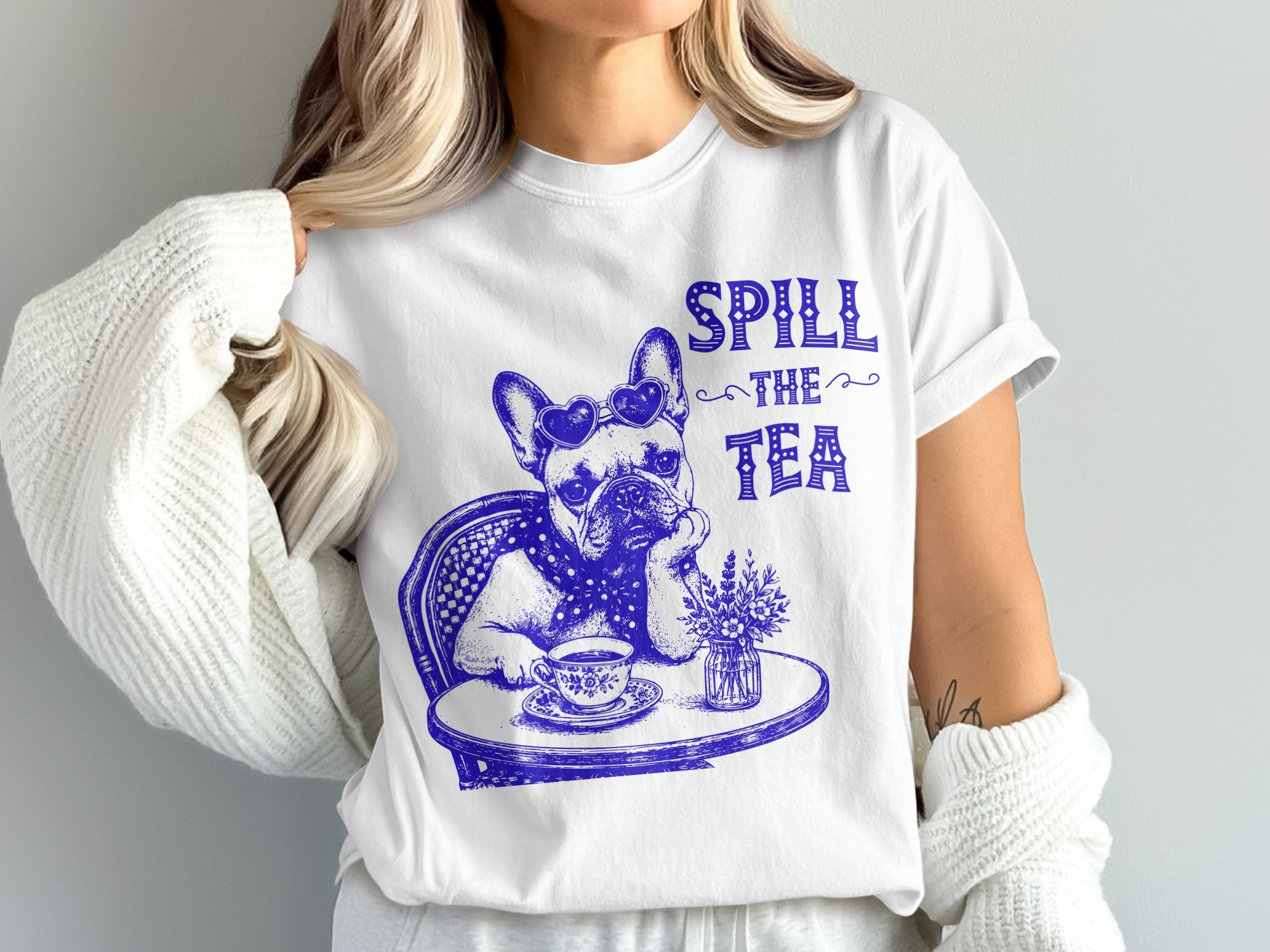 White t-shirt with blue graphic of dog wearing heart sunglasses, drinking tea, and text "SPILL the TEA".