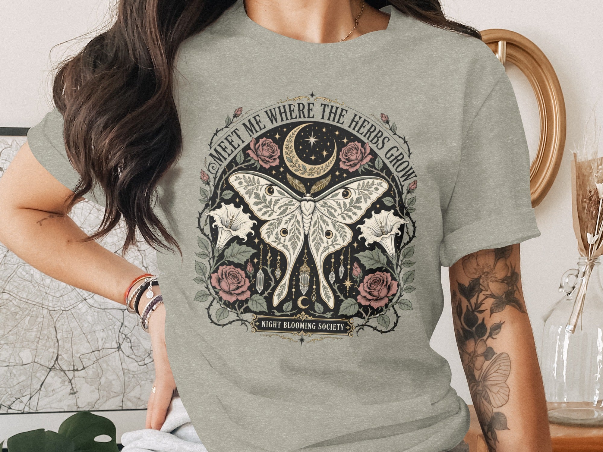 Grey t-shirt with mystical moth, roses, moon, stars, and "Meet Me Where the Herbs Grow" text.