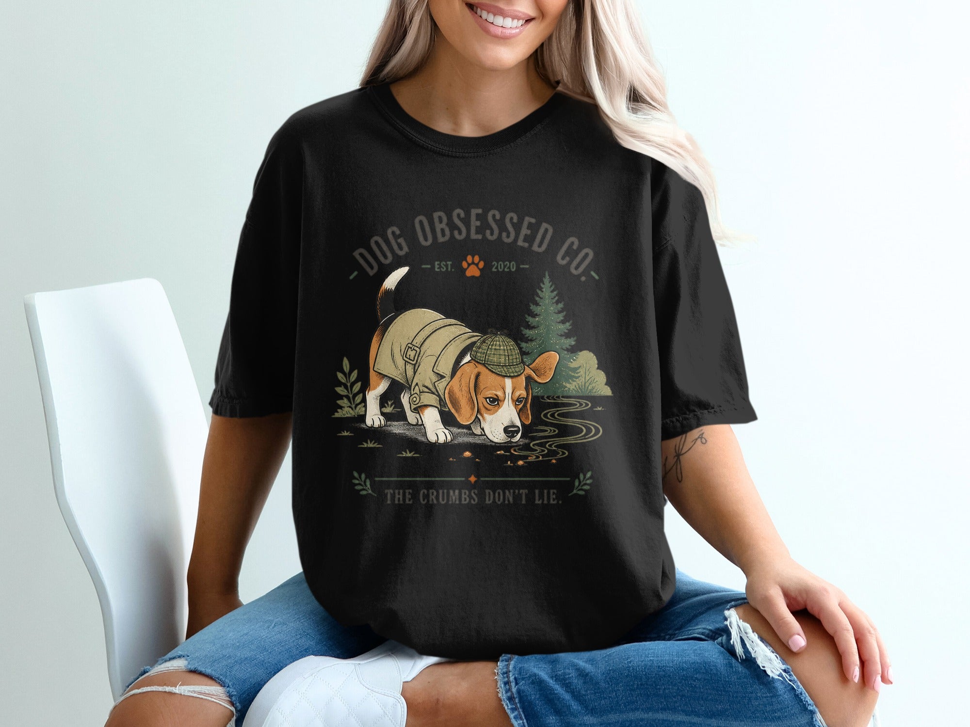 Black t-shirt with a beagle dog wearing a hat and jacket, smelling crumbs.