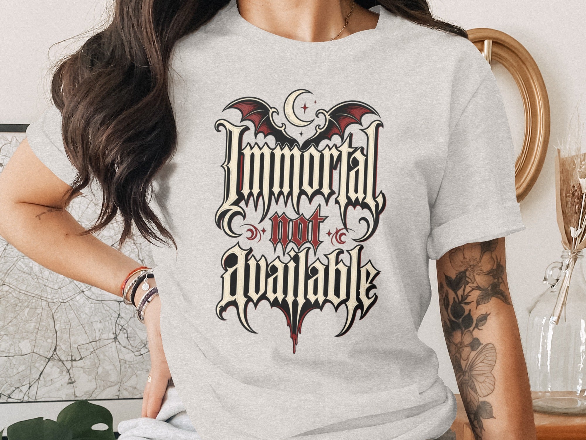 Light gray t-shirt with gothic text reading "Immortal not available" and bat wings.