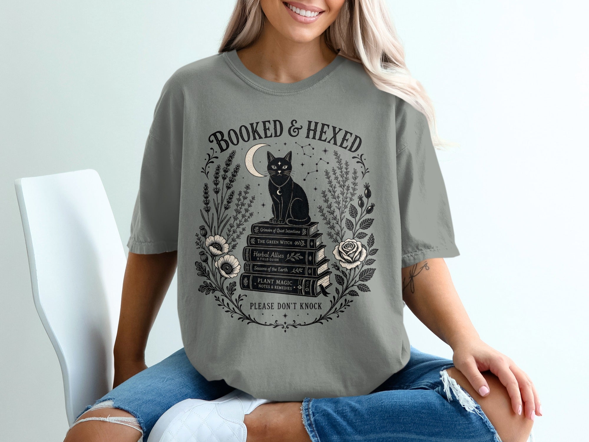 Grey t-shirt with "Booked & Hexed" design and a black cat on books.