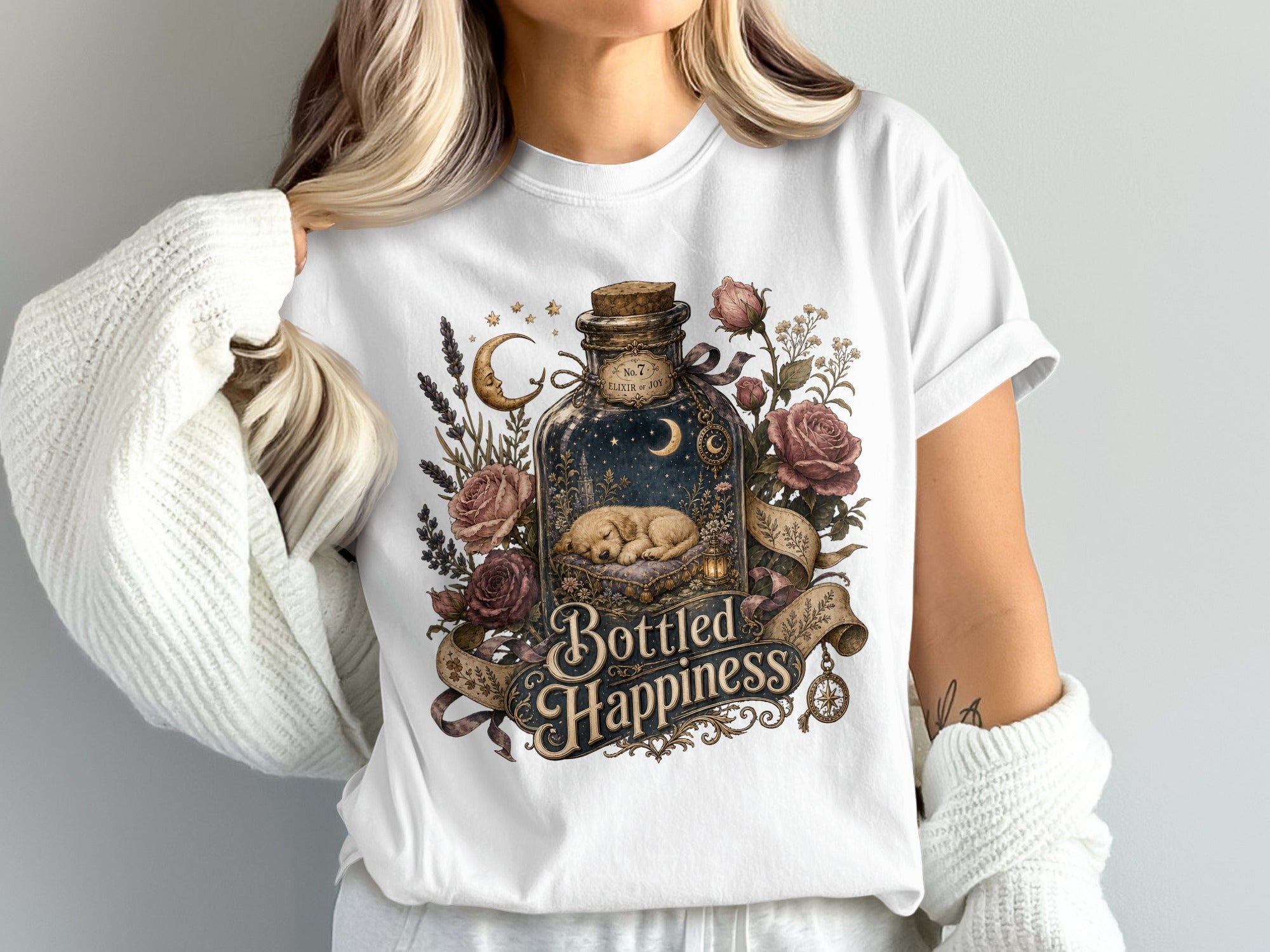 White t-shirt with "Bottled Happiness" design featuring a sleeping puppy in a starry bottle.