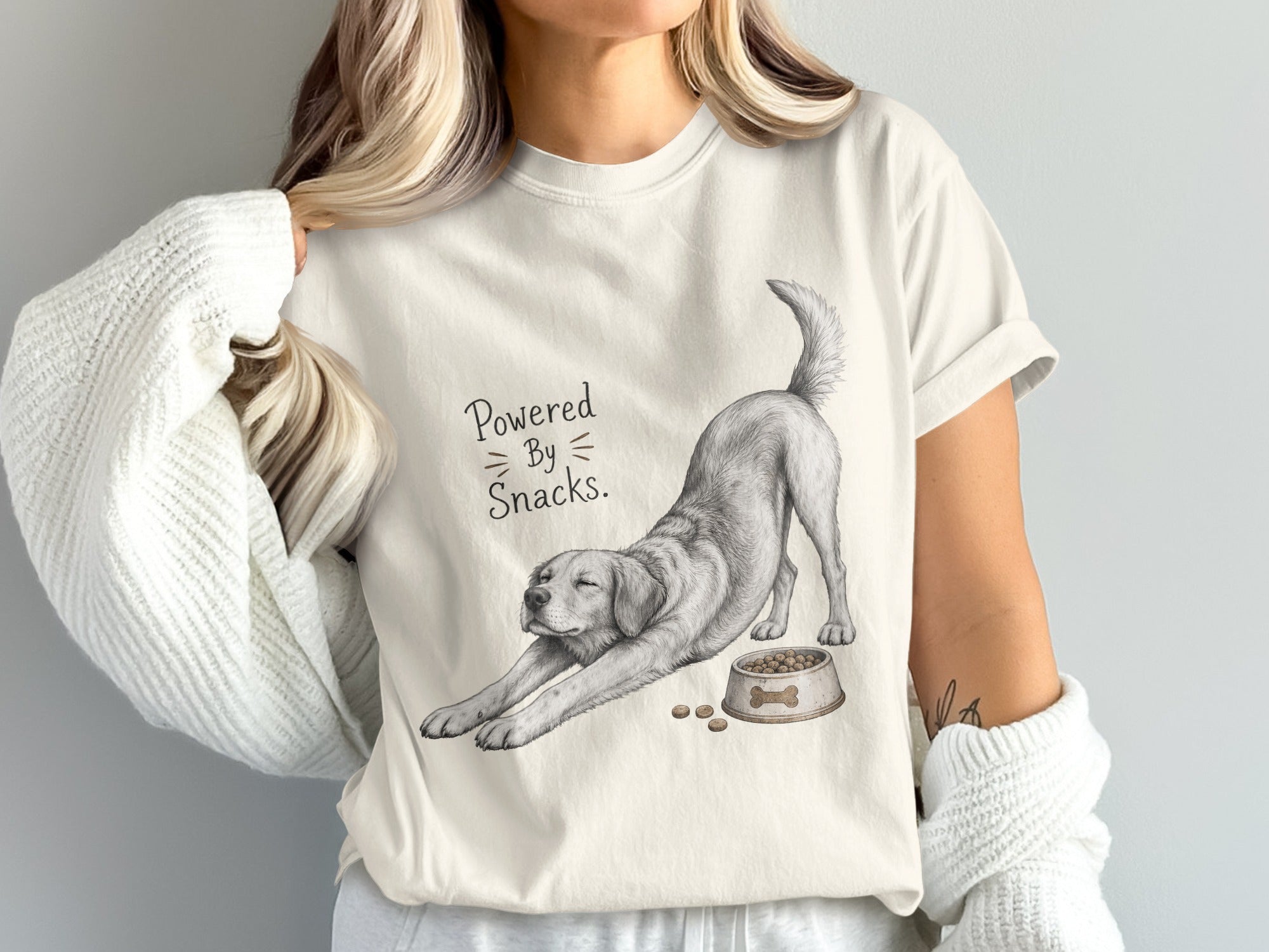 White t-shirt with sketch of a stretching dog and text "Powered By Snacks."