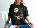 Black t-shirt with a spooky forest creature, full moon, and evergreen trees graphic.