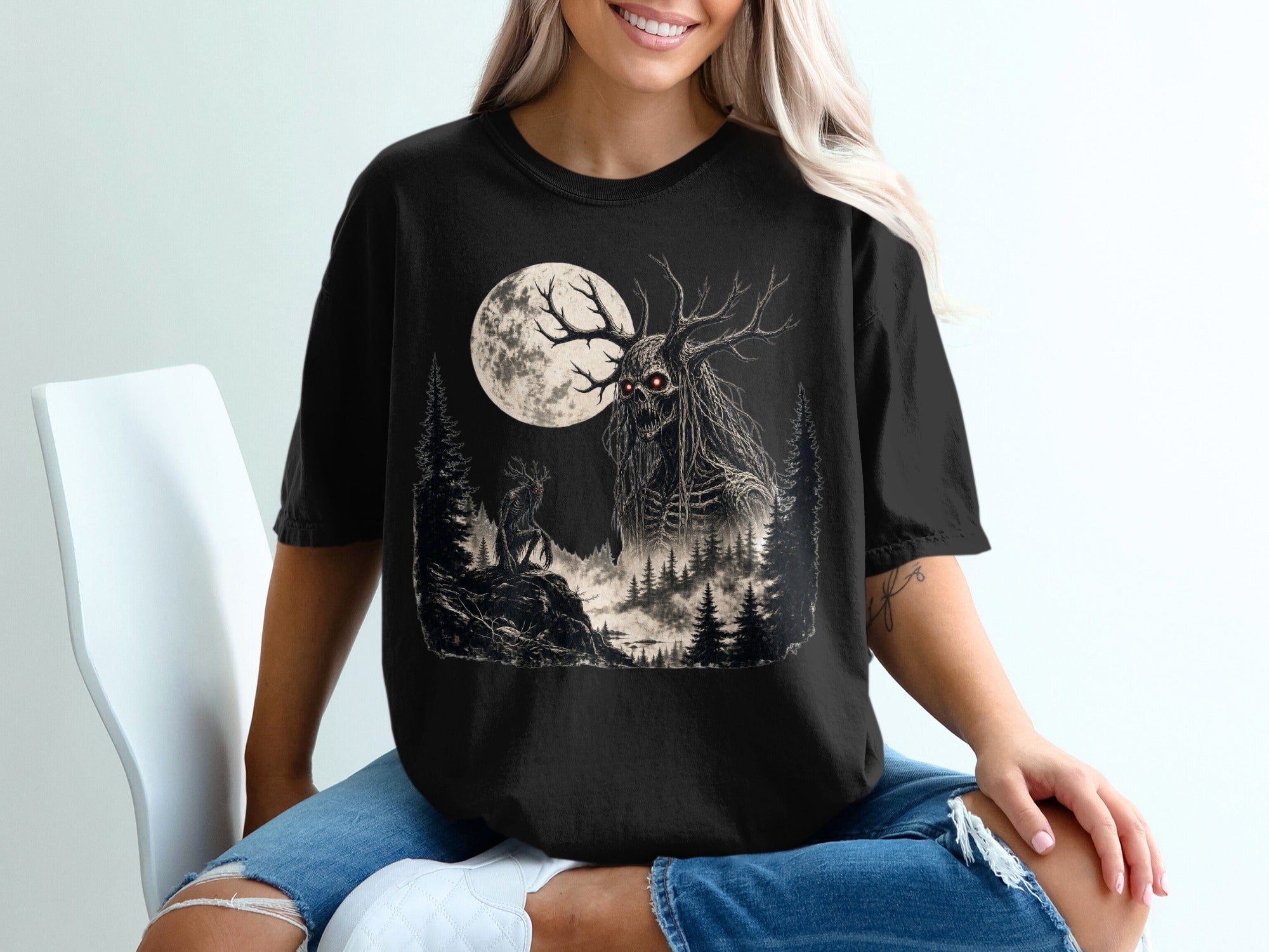 Black t-shirt with a spooky forest creature, full moon, and evergreen trees graphic.
