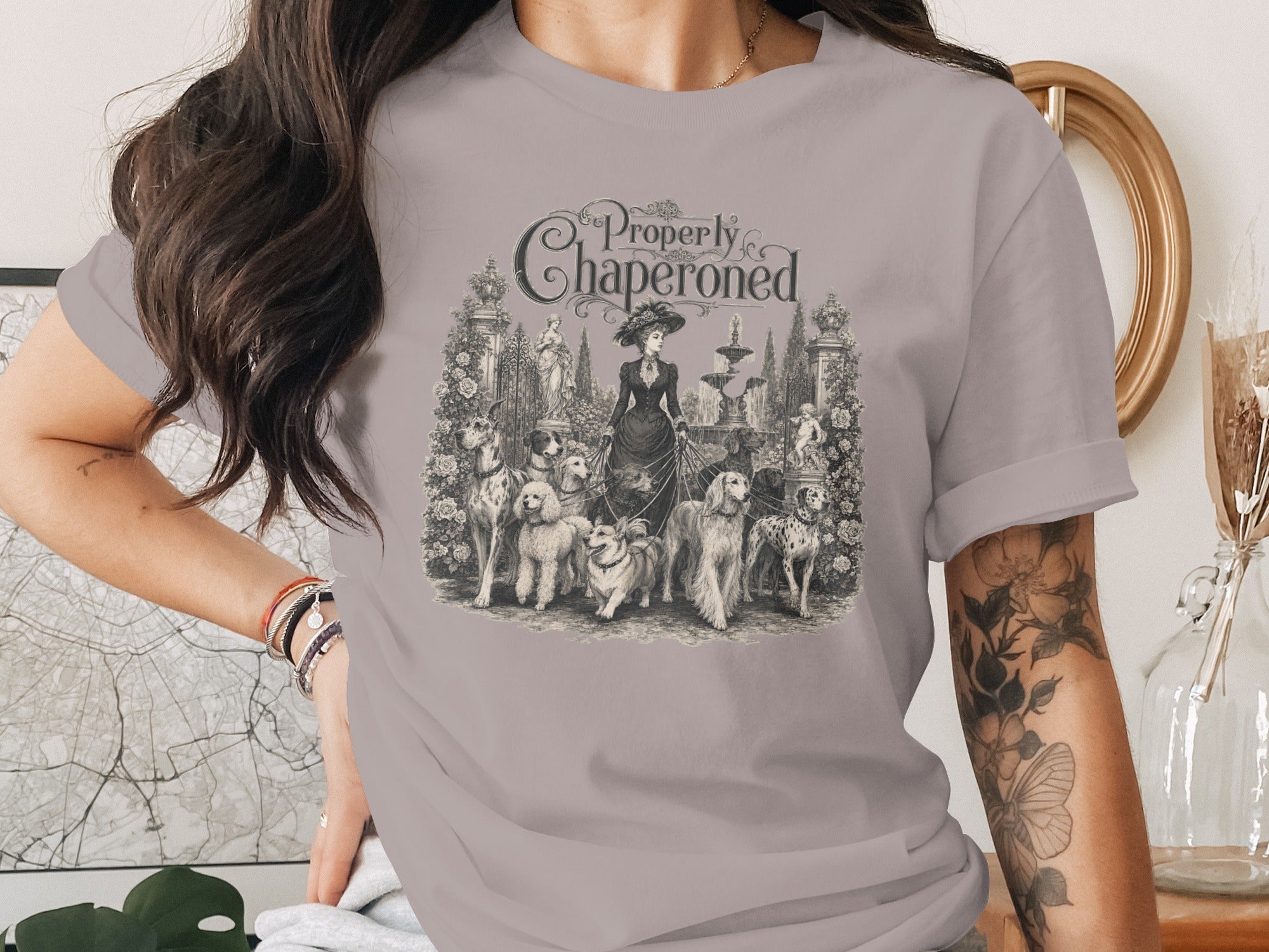 T-shirt graphic: "Properly Chaperoned" with a woman and multiple dogs in a garden.