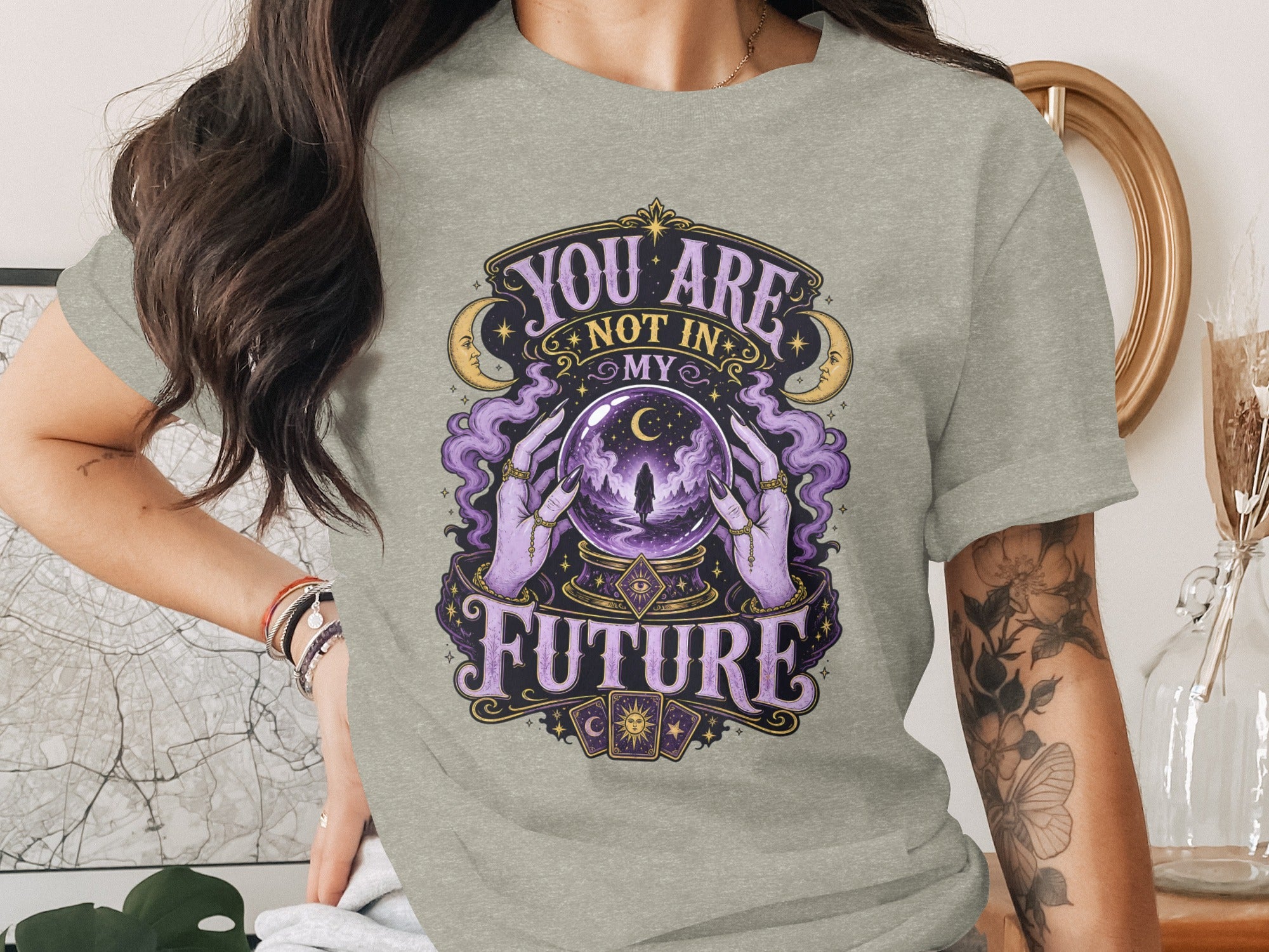 A woman wears a gray t-shirt with an illustration of hands holding a crystal ball and the text "You are not in my future".