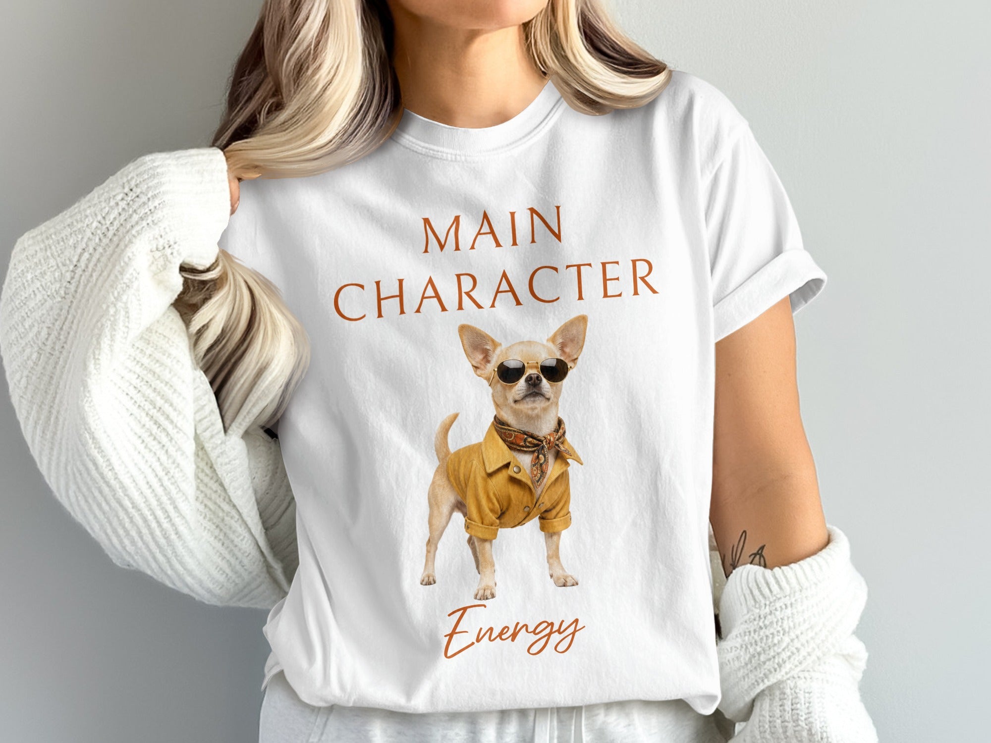 White t-shirt with "MAIN CHARACTER ENERGY" text and a chihuahua wearing sunglasses and a jacket.