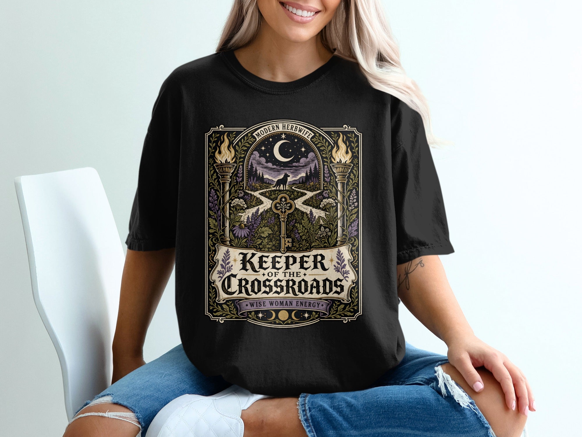 Black t-shirt with "Keeper of the Crossroads" and "Wise Woman Energy" text and woodland scene.