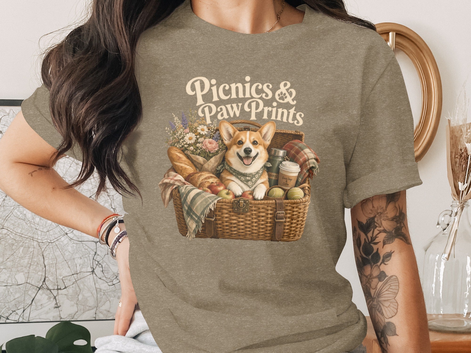 "Picnics & Paw Prints" text above a corgi in a picnic basket with flowers, bread, apples, and coffee.