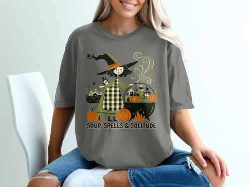 Graphic tee with witch, pumpkins, cauldron, and text "SOUP, SPELLS & SOLITUDE".