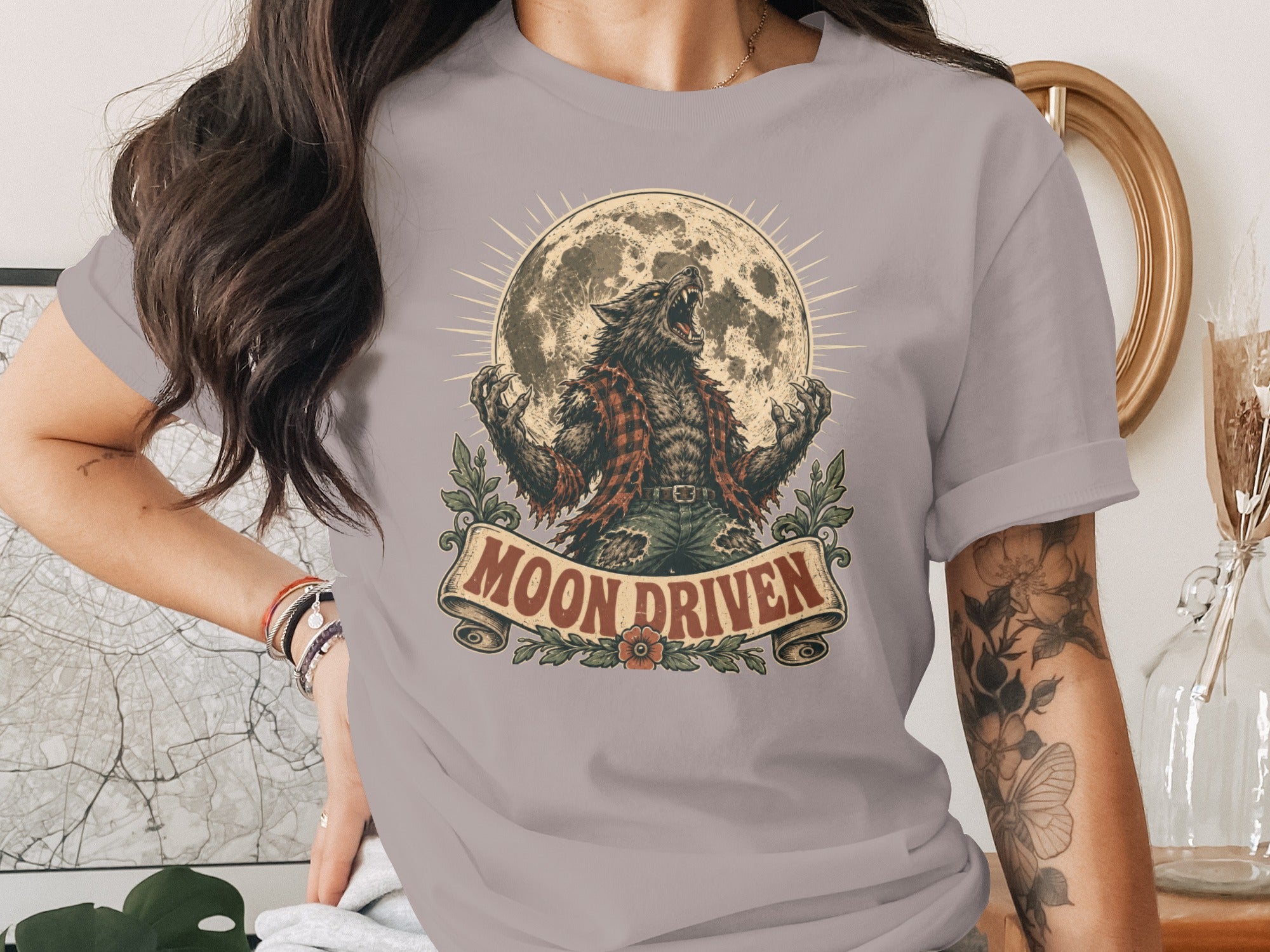 Werewolf howling at full moon with "Moon Driven" text on a grey t-shirt.
