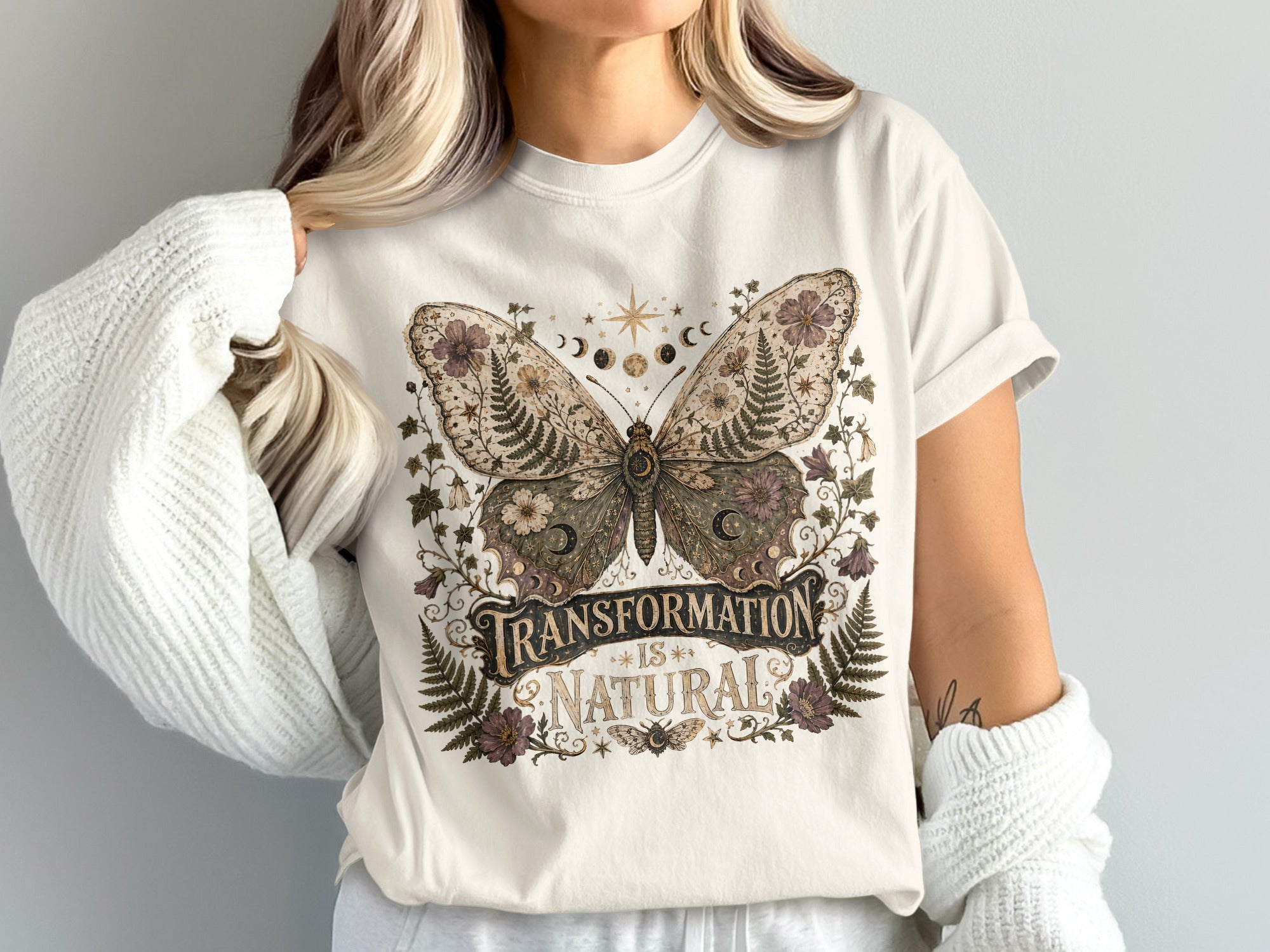 White t-shirt with a vintage-style butterfly graphic and text "Transformation is Natural."