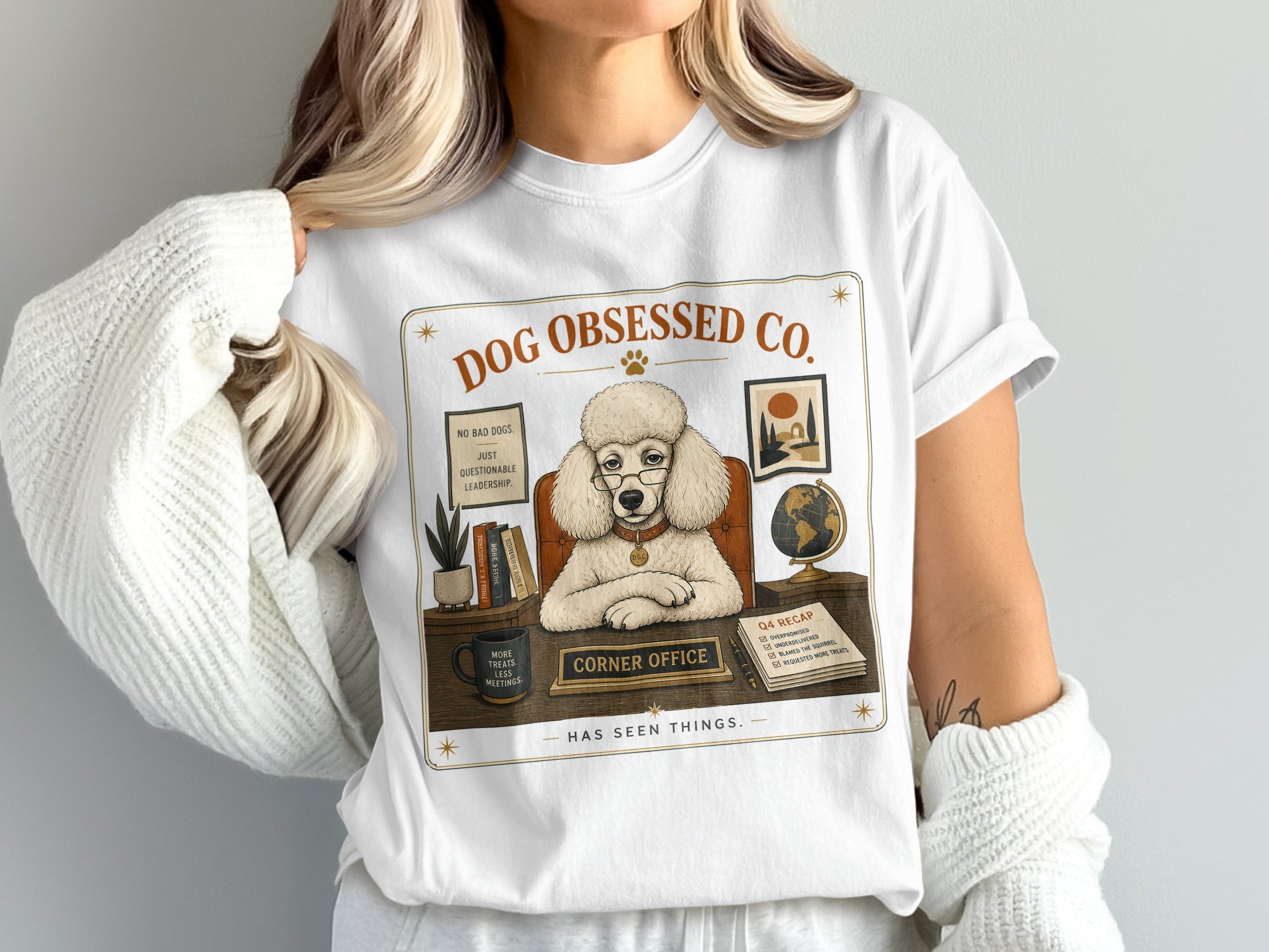 White t-shirt with "Dog Obsessed Co." graphic of a poodle in a corner office.