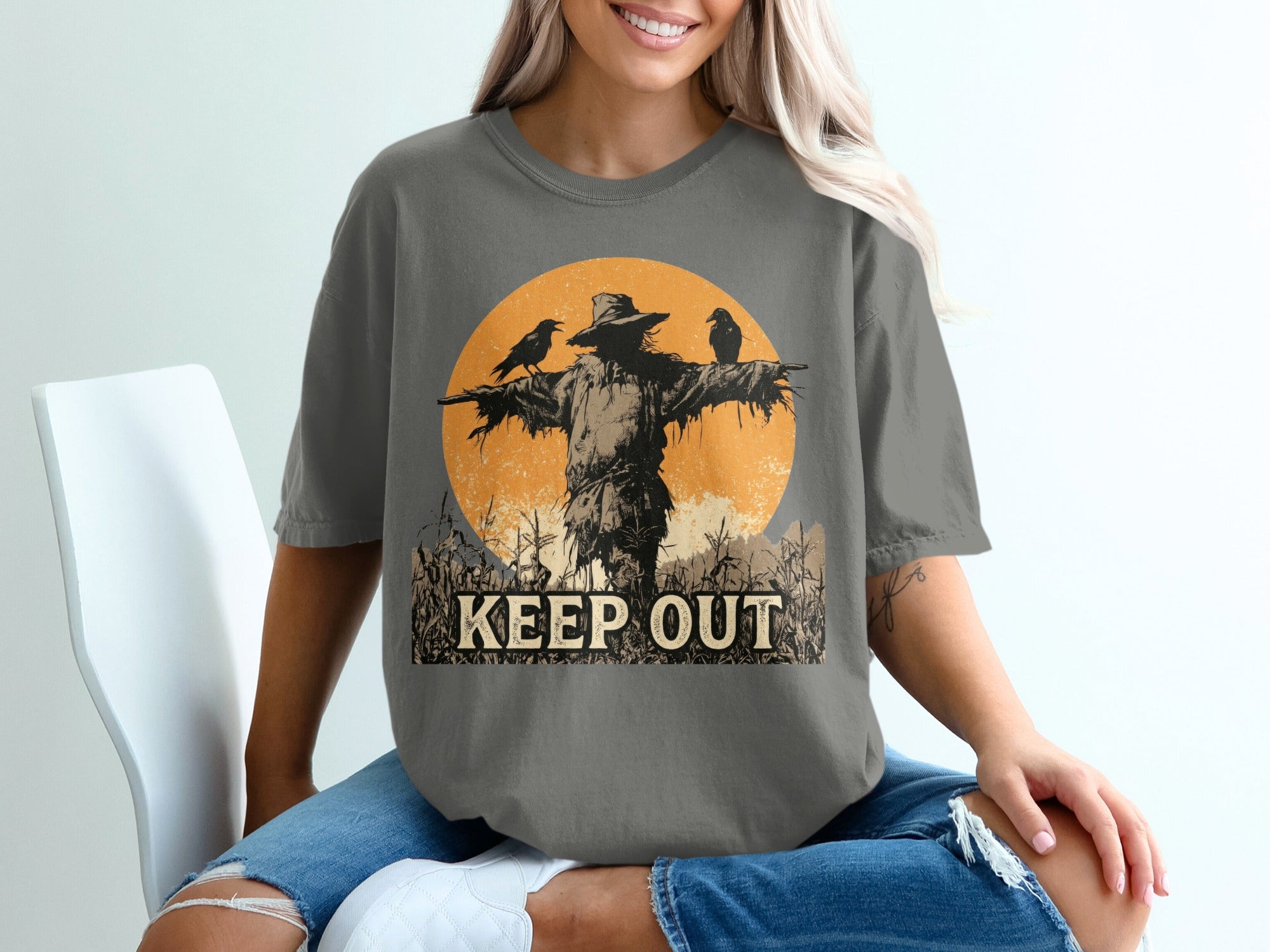 Scarecrow with crows and "KEEP OUT" text on a distressed circular background.