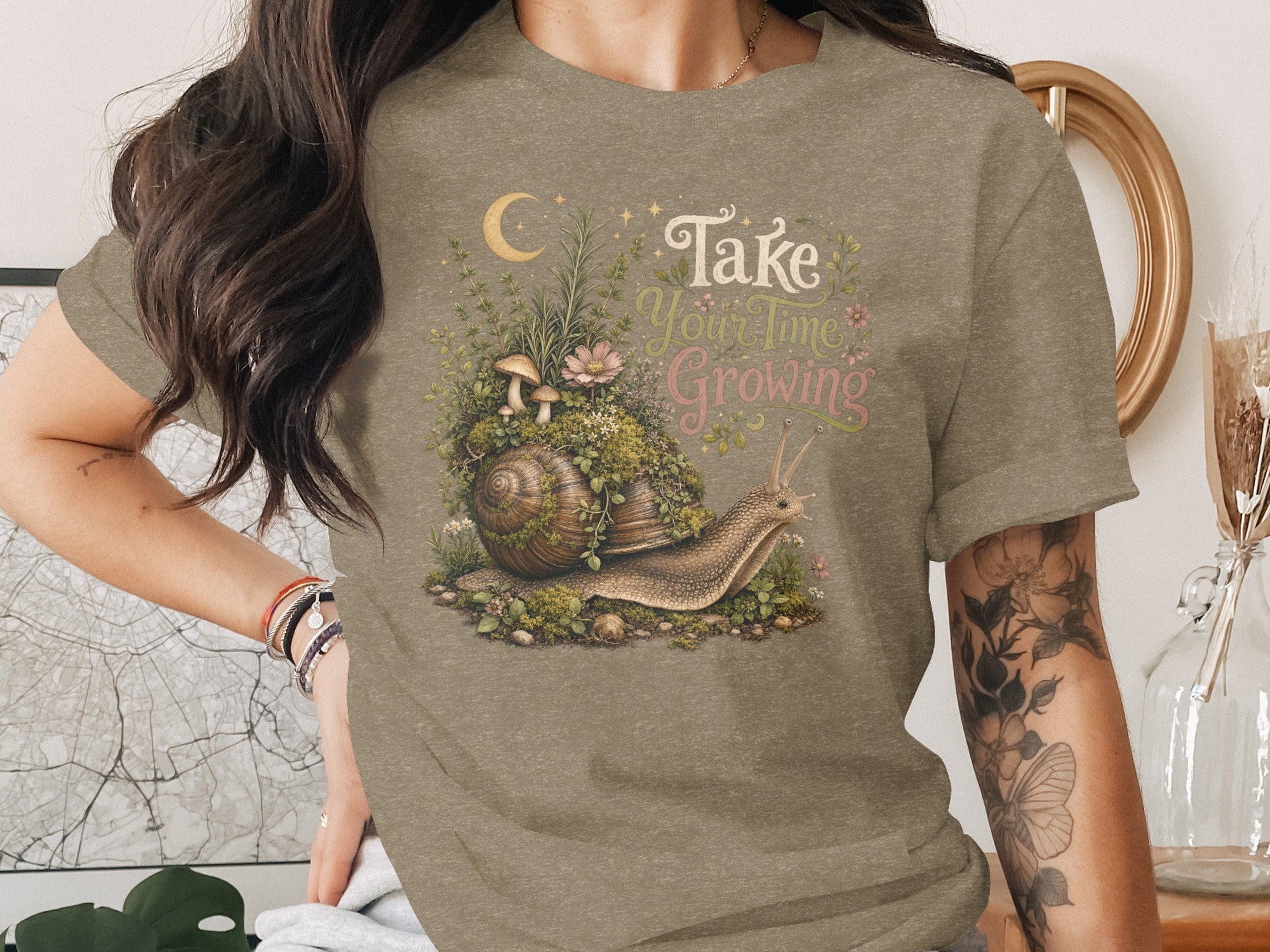 T-shirt with snail, mushrooms, plants, moon, stars and text "Take Your Time Growing".