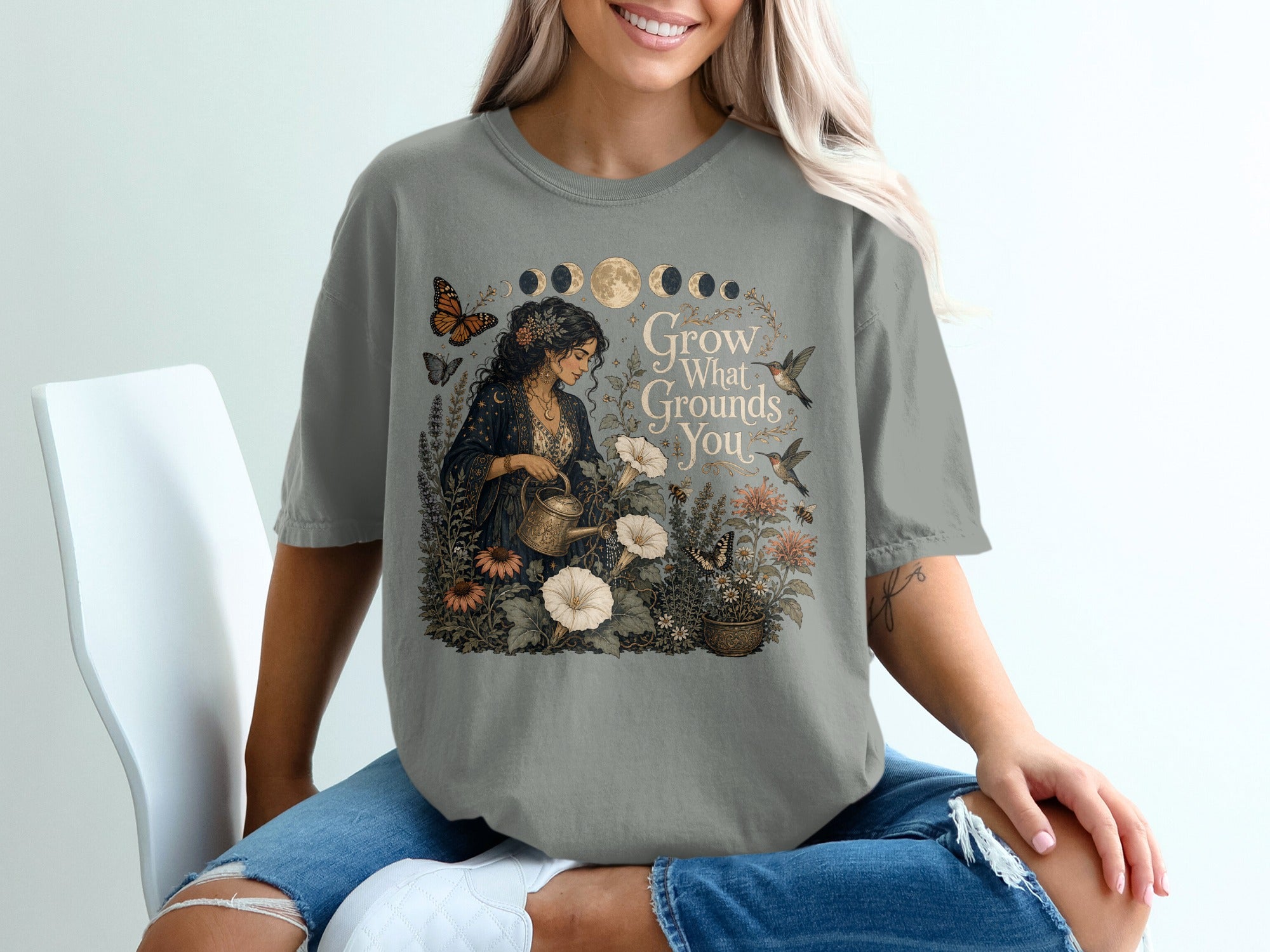 T-shirt graphic features a woman watering flowers with text "Grow What Grounds You".