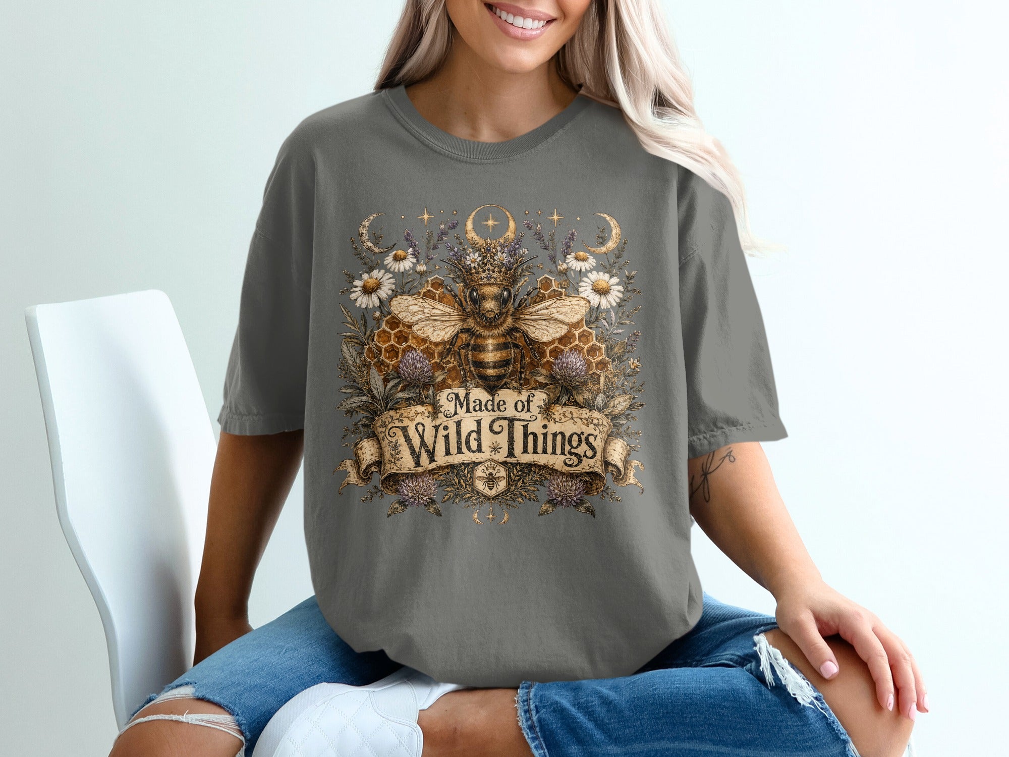 T-shirt with a crowned bumblebee, flowers, moons, and text "Made of Wild Things."