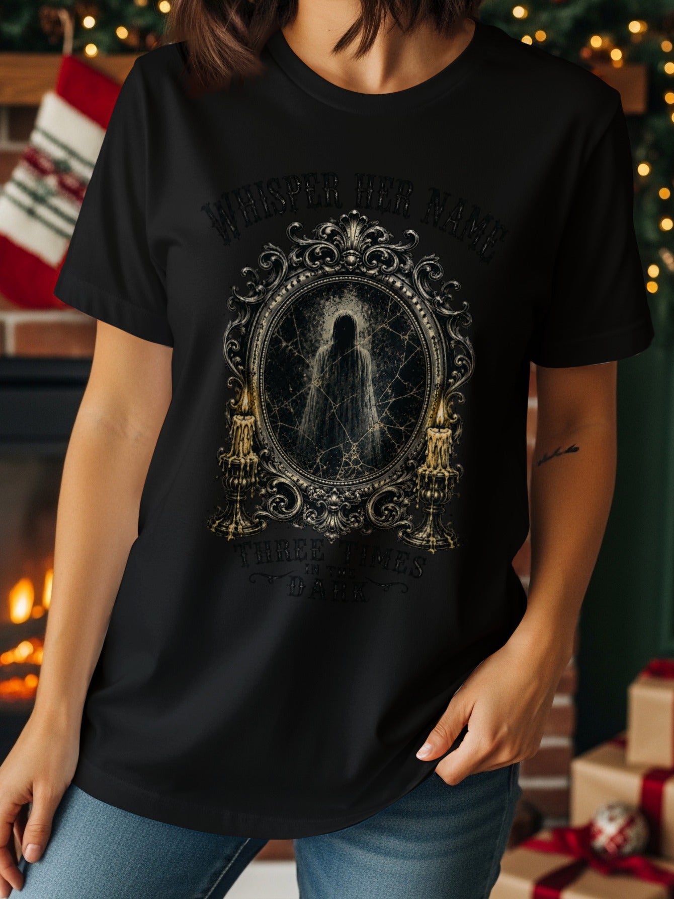 Black t-shirt with ornate frame, ghost, candles, and text "Whisper Her Name Three Times In The Dark".