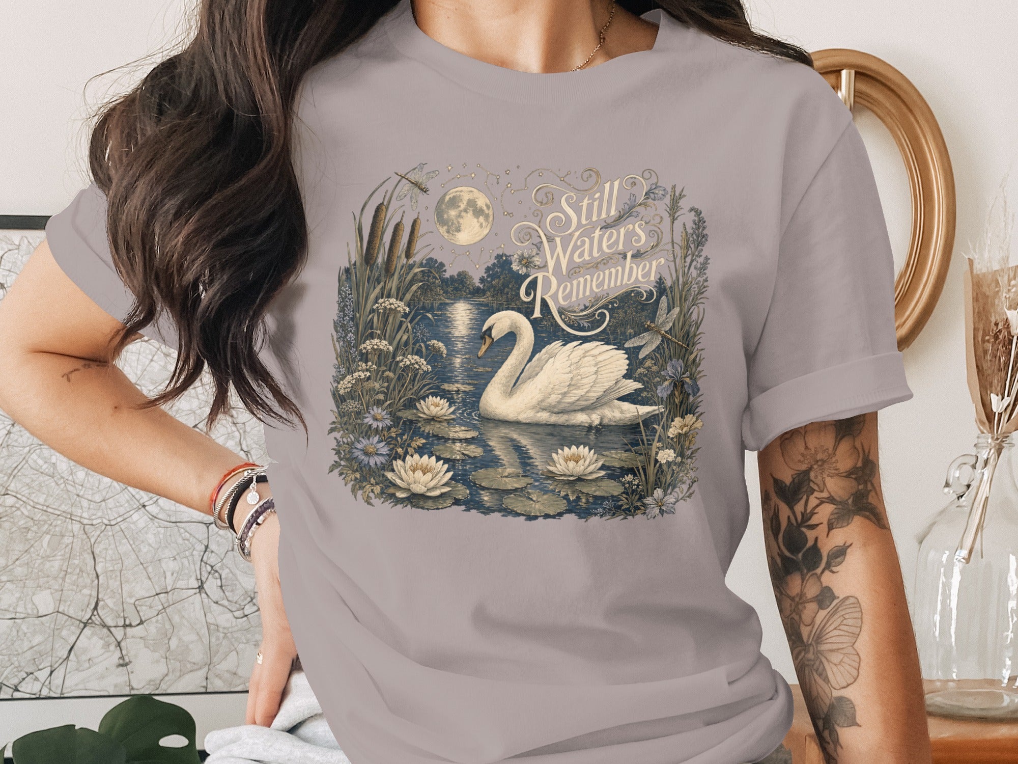 T-shirt with a swan and water lilies on a lake under a full moon with text.