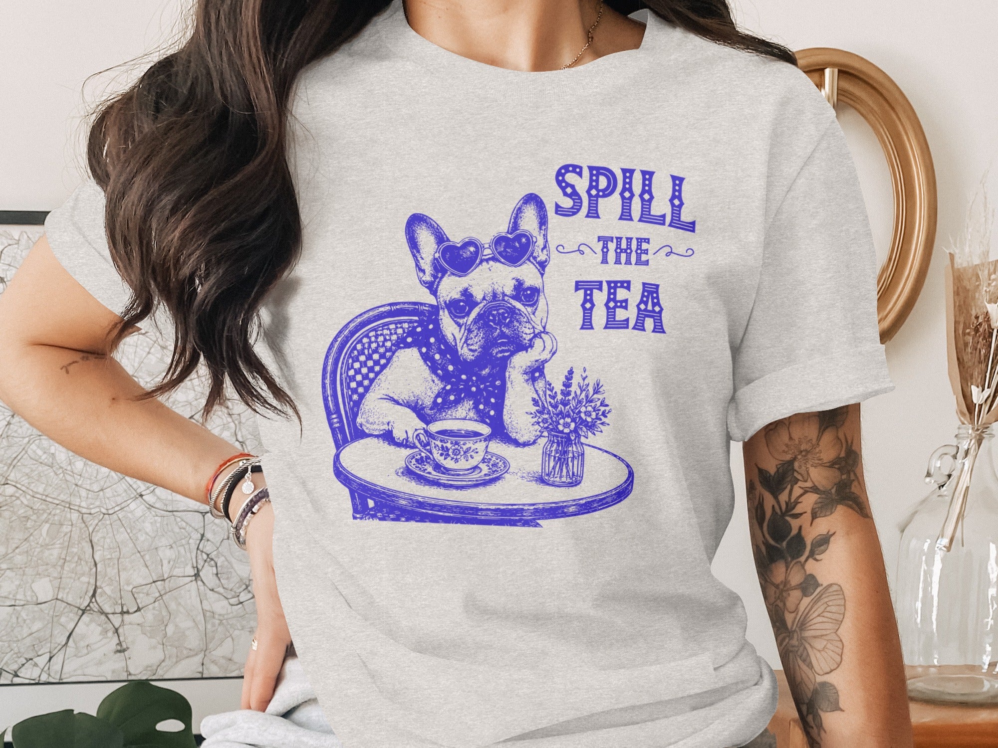 French bulldog wearing heart sunglasses, sitting at a table, with "Spill the Tea" text.