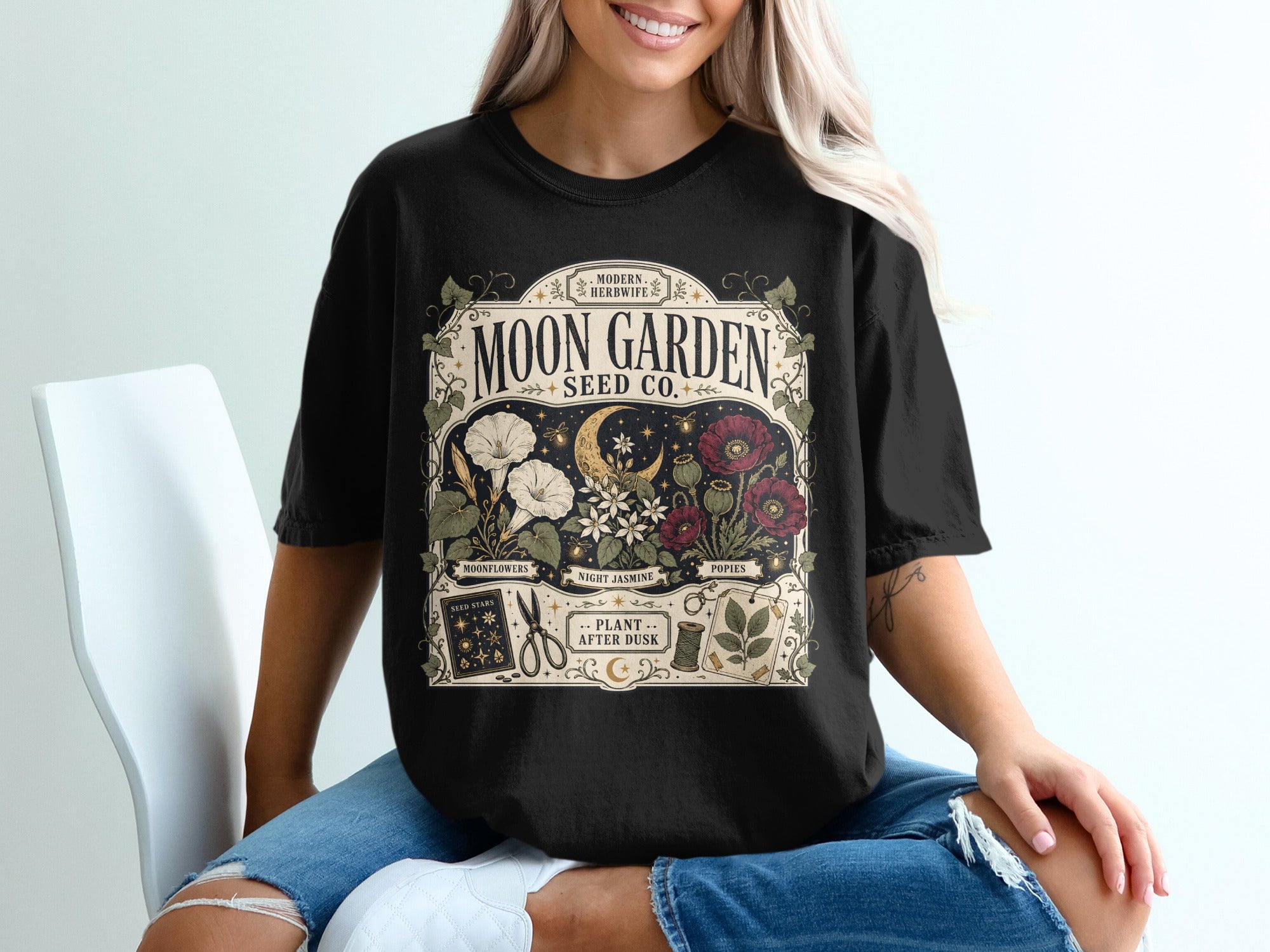 Black t-shirt with "Moon Garden Seed Co." design, moon, flowers, and gardening tools.
