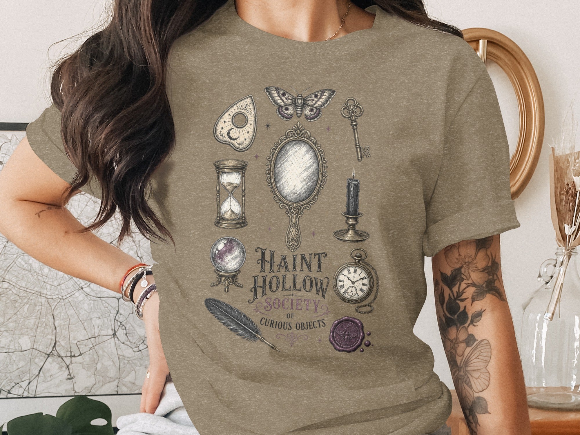 T-shirt graphic with Ouija board, moth, key, mirror, candle, hourglass, crystal ball, feather, pocket watch, and stamp.