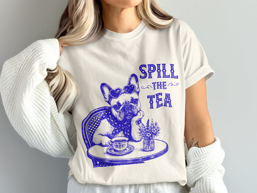 French bulldog sitting at a table, wearing heart sunglasses, with "Spill the Tea" text.