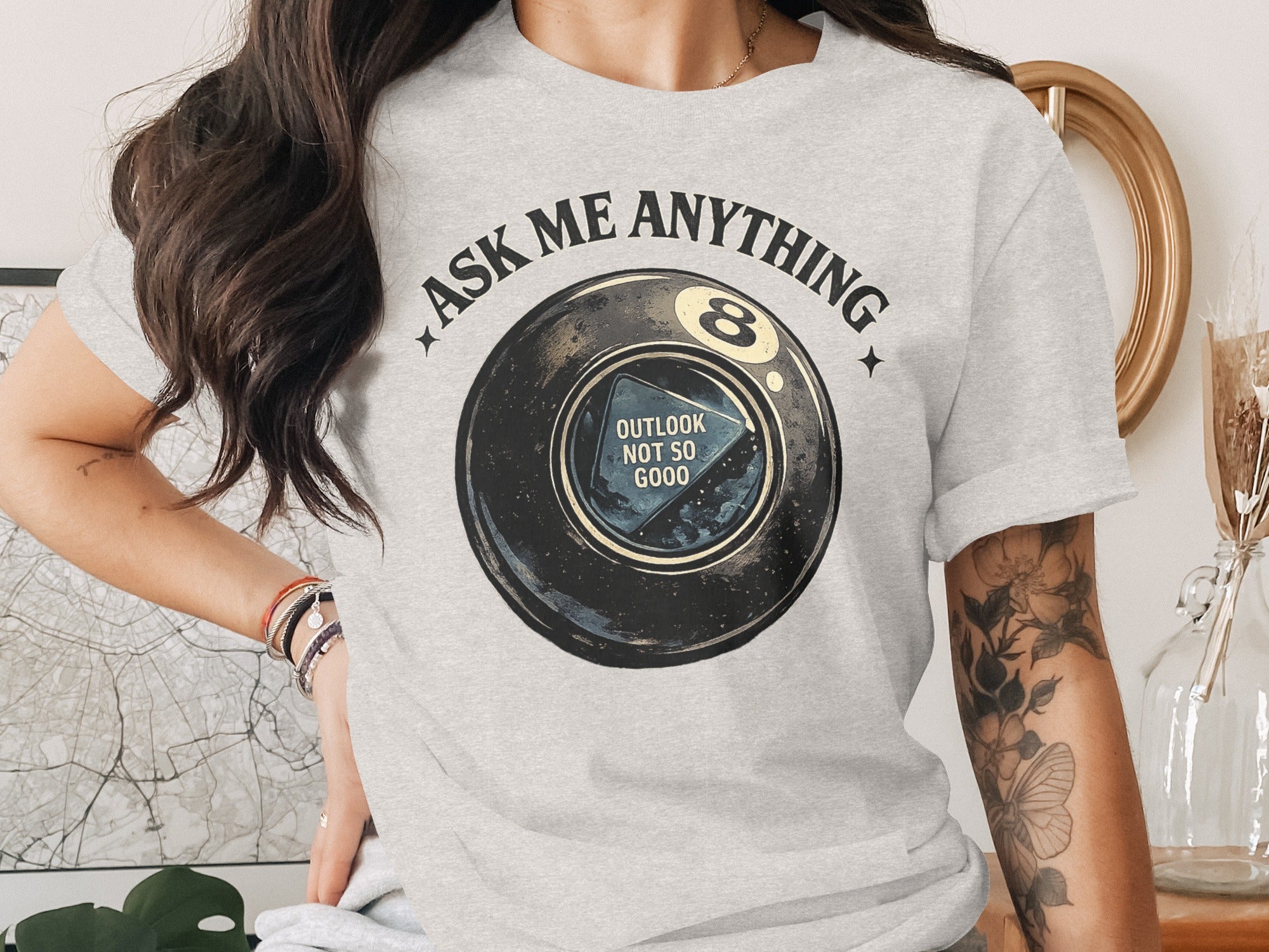 T-shirt with graphic of a Magic 8 Ball and "OUTLOOK NOT SO GOOD" text.