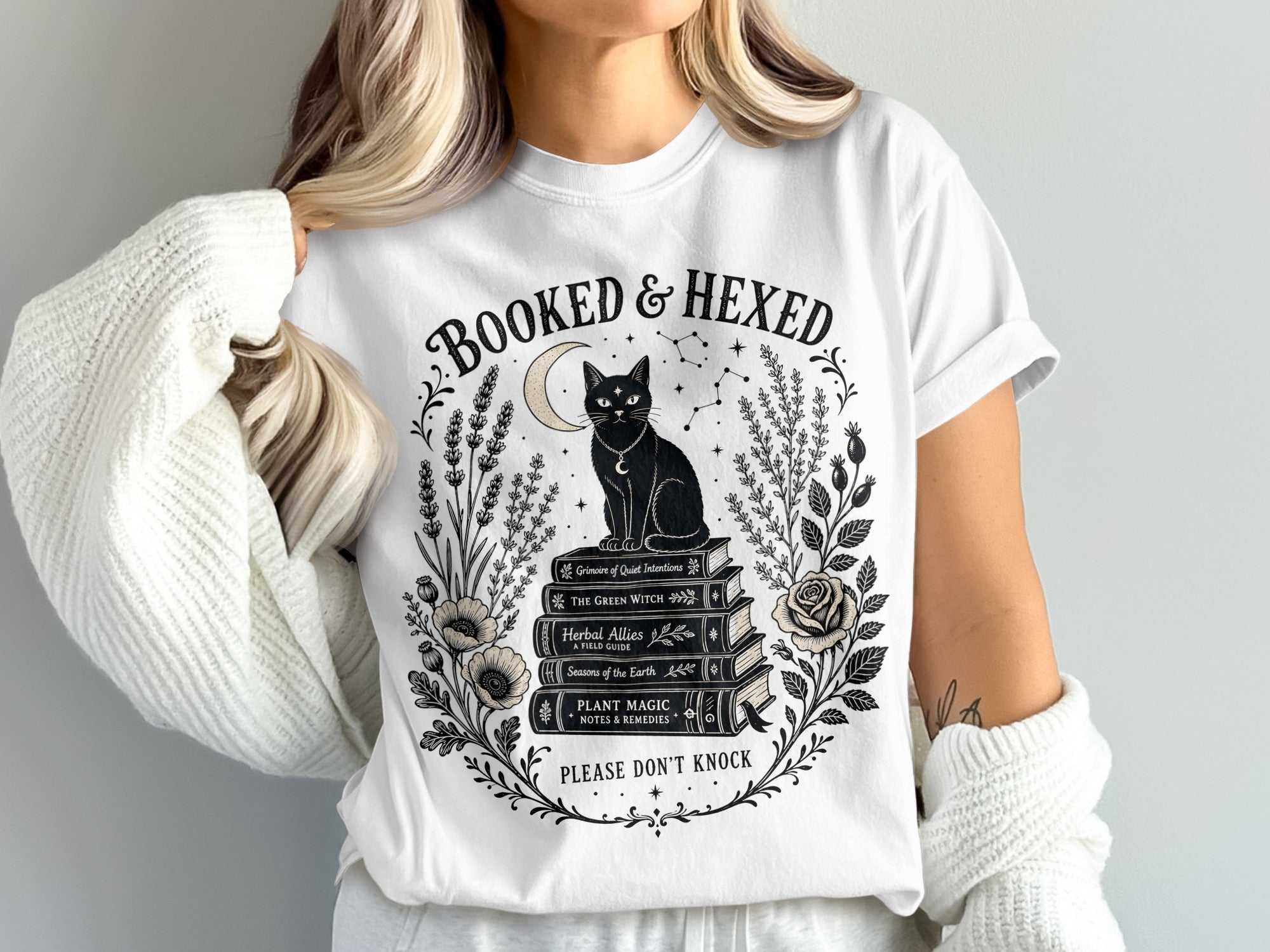 White t-shirt with "Booked & Hexed" design featuring a black cat on books.