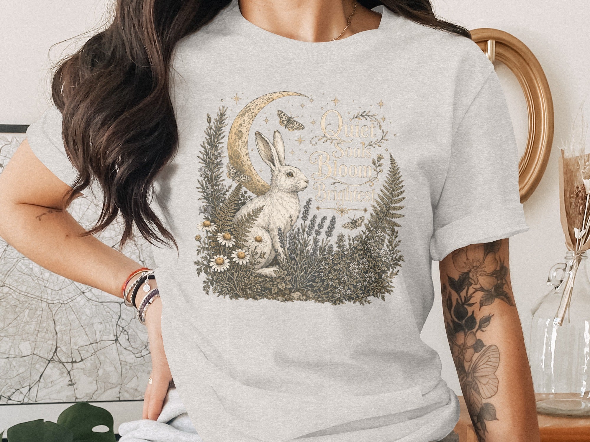 T-shirt graphic: rabbit, moon, flowers, ferns, and text "Quiet Souls Bloom Brightest".