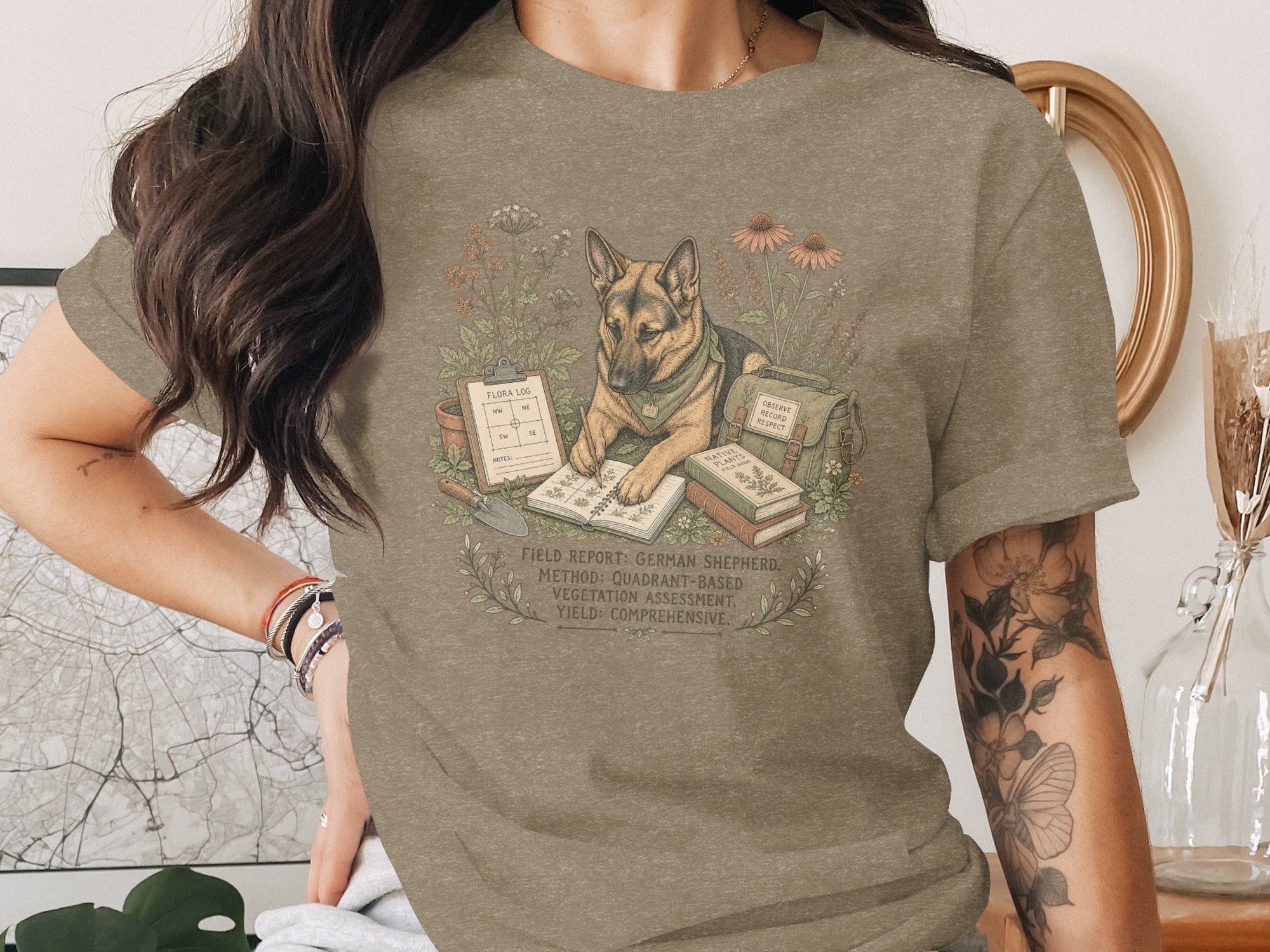 German Shepherd reading next to field guide with flora log and gardening tools.