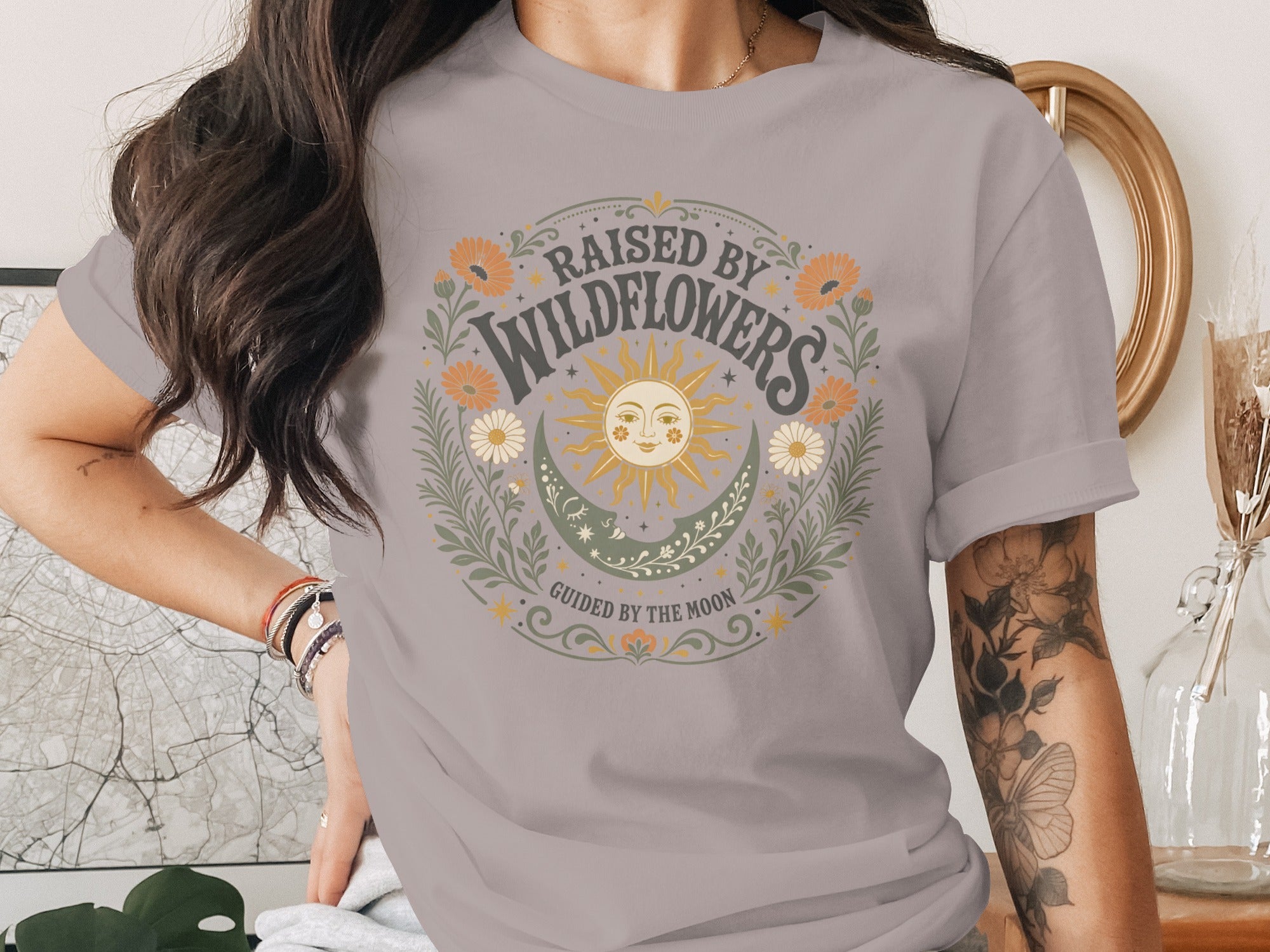 Gray t-shirt with "Raised by Wildflowers Guided by the Moon" floral design.