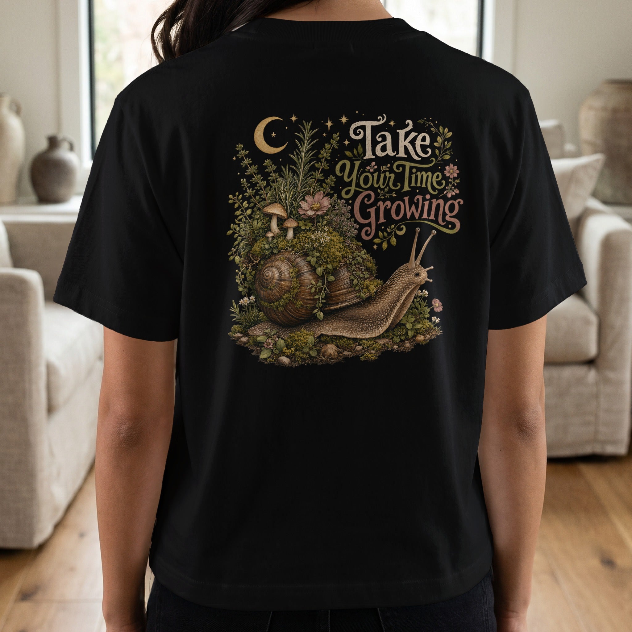 Snail with moss, mushrooms, and flowers, text "Take Your Time Growing" on black shirt.