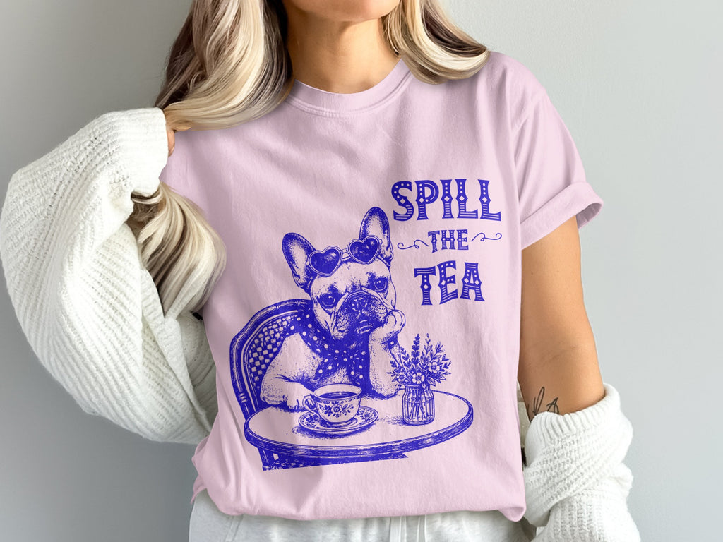 French bulldog wearing heart sunglasses sits at table with tea, "Spill the Tea" text.