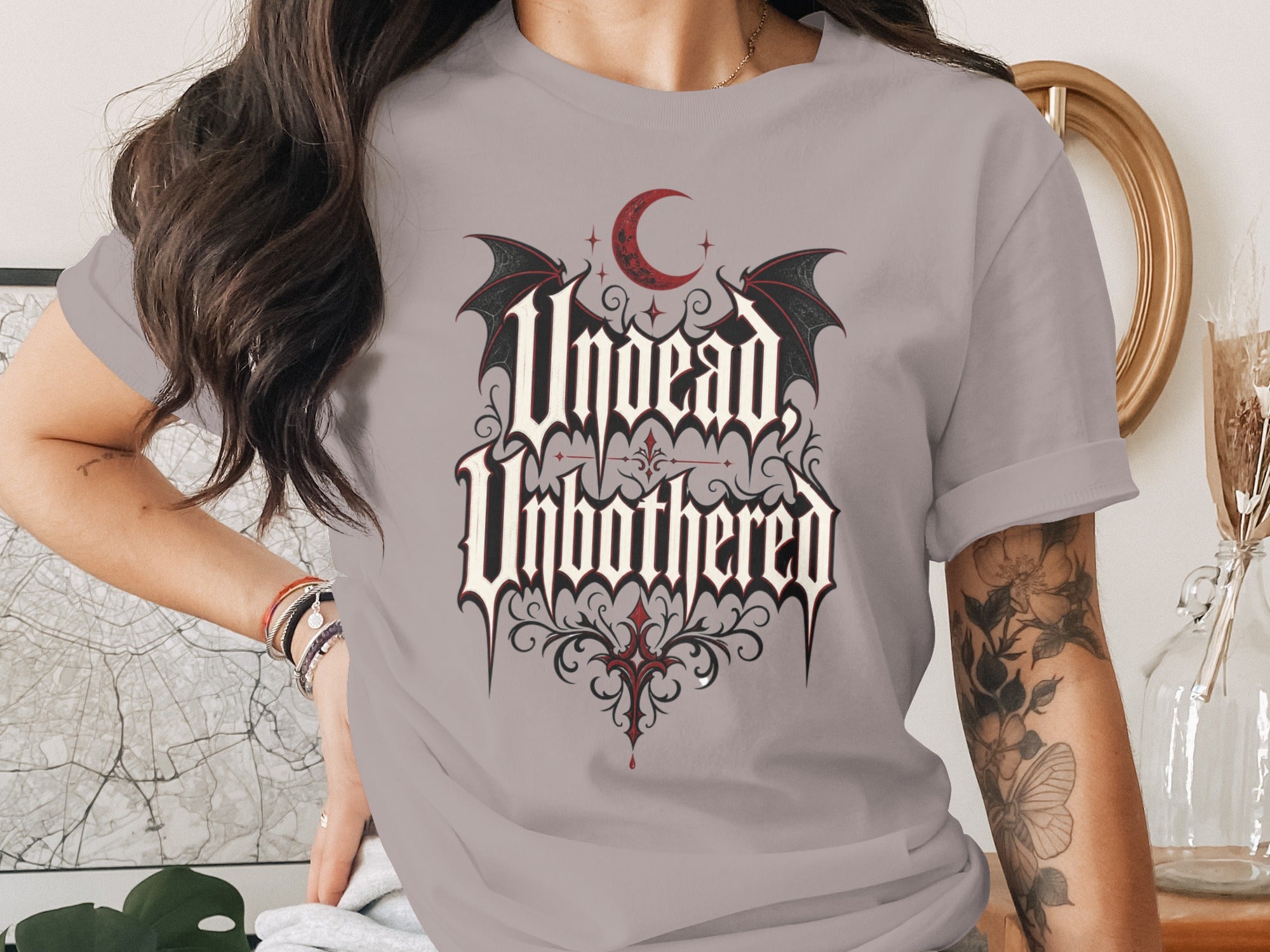 T-shirt with gothic script "Undead Unbothered" design featuring bats and a crescent moon.